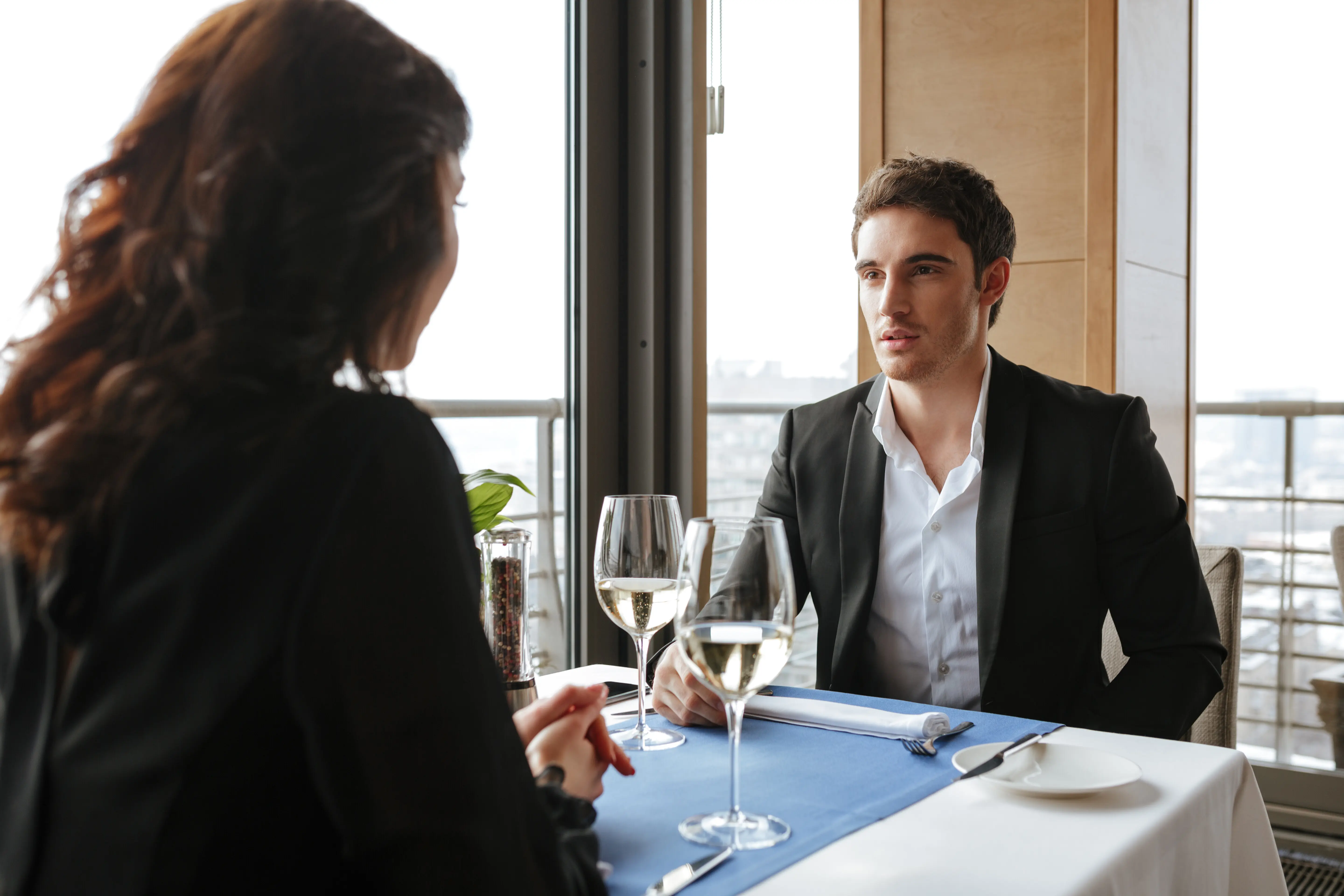 Photo taken from behind a woman with a man in a restaurant.