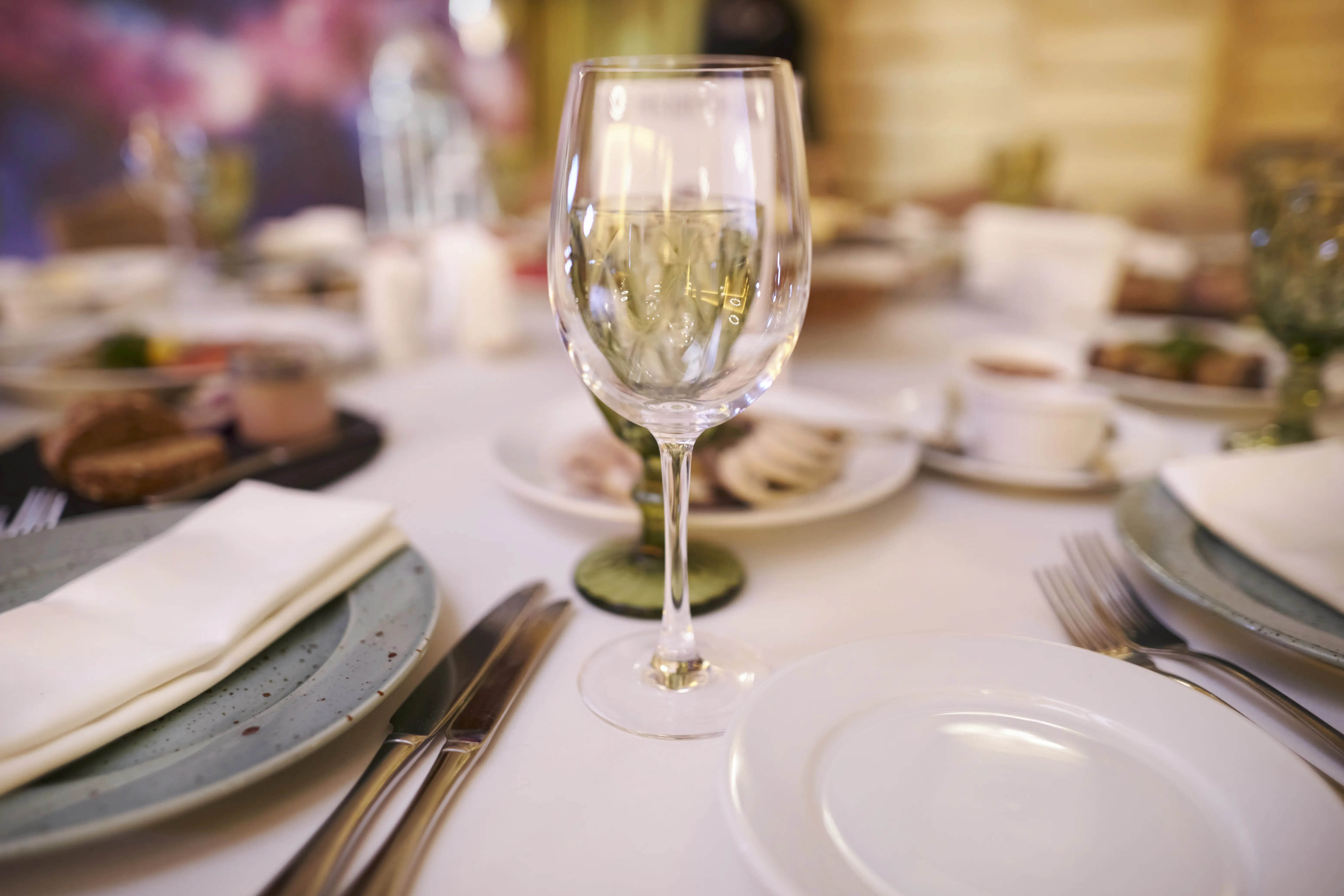 An empty wine glass sits on a set table; close-up of the dining table decoration.