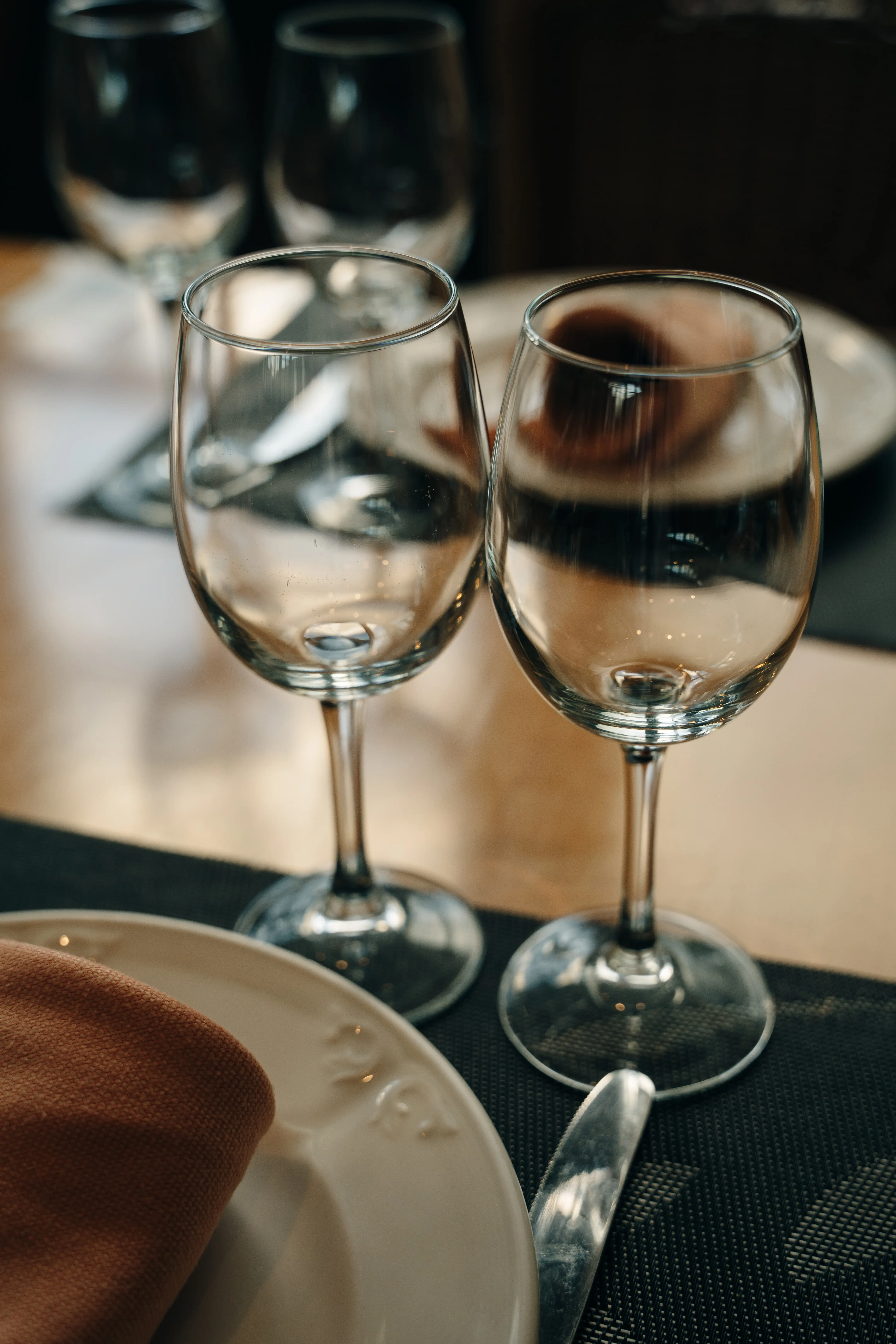 Crystal or glass goblets on tables set with white ceramic plates.